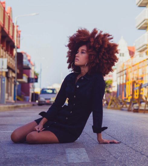 woman in black long sleeve shirt sitting on sidewalk during daytime