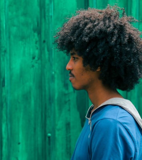 man facing right near green wall