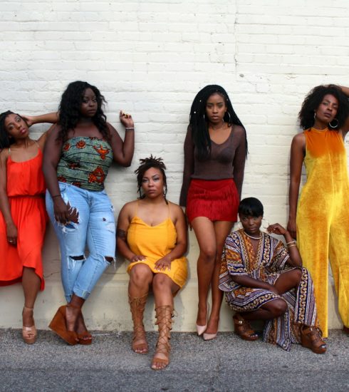 six women leaning on white wall
