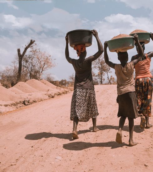 three women carrying basin while walking barefoot