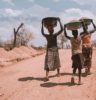 three women carrying basin while walking barefoot