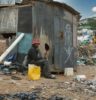 man in black jacket sitting on ground near garbage