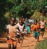 children running and walking on brown sand surrounded with trees during daytime